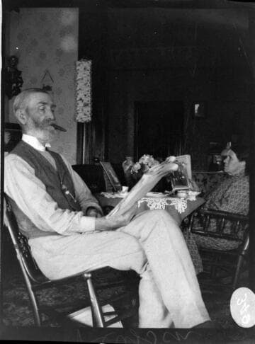 A couple sitting around a tea table. The elderly man