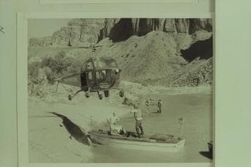 Red Carson piloting the helicopter over the "Esmeralda" at the head of Hance Rapid. Joe Desloge and Ed Hudson are in the boat. Marston and Taylor in the background