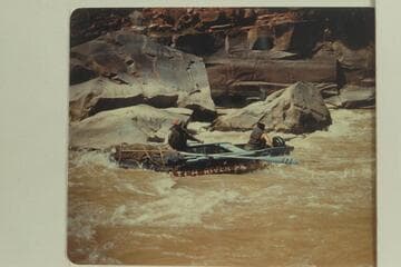 Bus Hatch runs his 10-man inflated boat bow-first and with oars through Triplett Falls while Lloyd Shearer holds the outboard motor clear of the rocks. The motor was not used in the navigation of the rapid