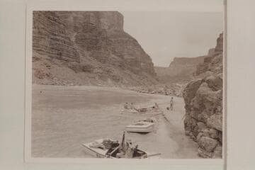 The beach below Mile 24.5 Rapid at Tanner Wash. Stop of Nevills party for lunch on 7/13/47. Francis Farquhar rigs tripod in boat in foreground, Garth Marston and Marjorie Farquhar on stern of boat in background and Margaret Marston on beach